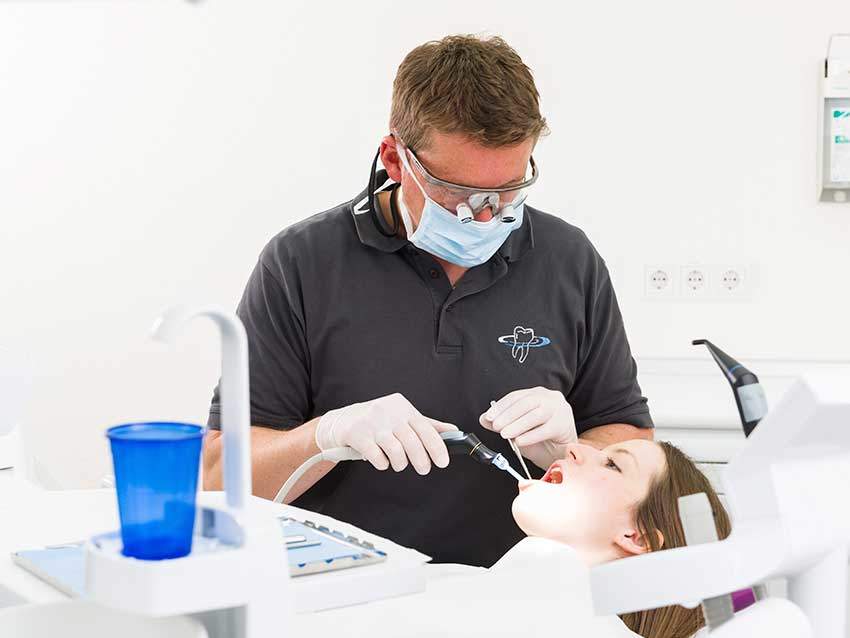Zahnarzt behandelt junge Frau.